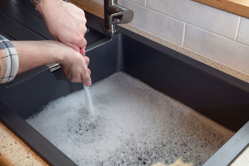 Hands Using a Plunger in a Kitchen Sink — Full On Plumbing & Gas in Winnellie, NT