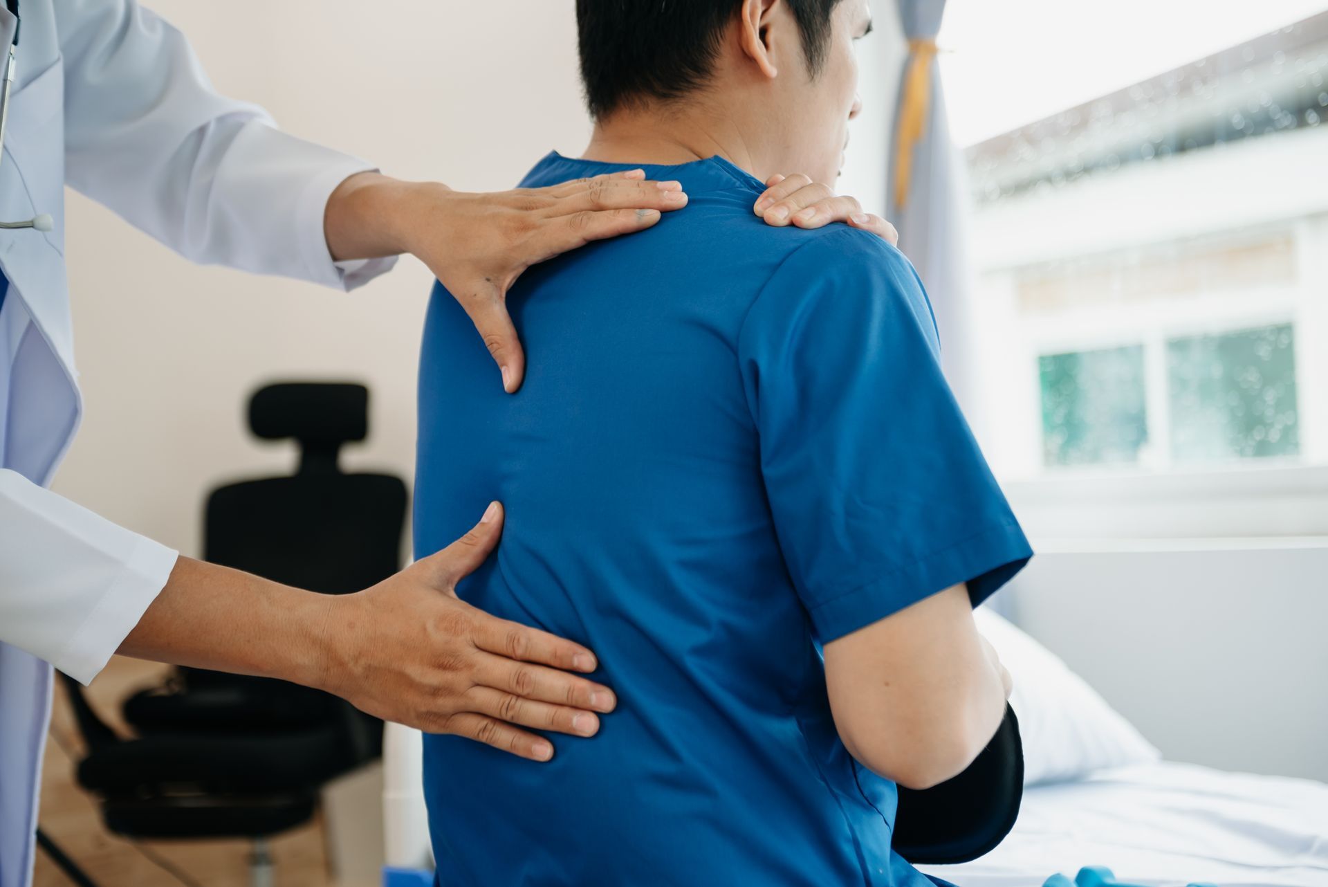A doctor is examining a patient 's back in a hospital.