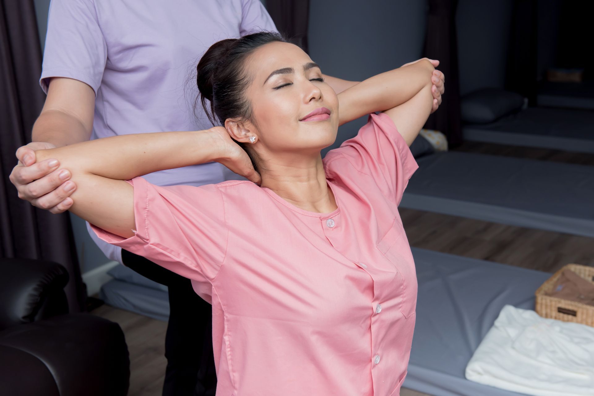 A woman is getting a massage in a spa with her arms outstretched.