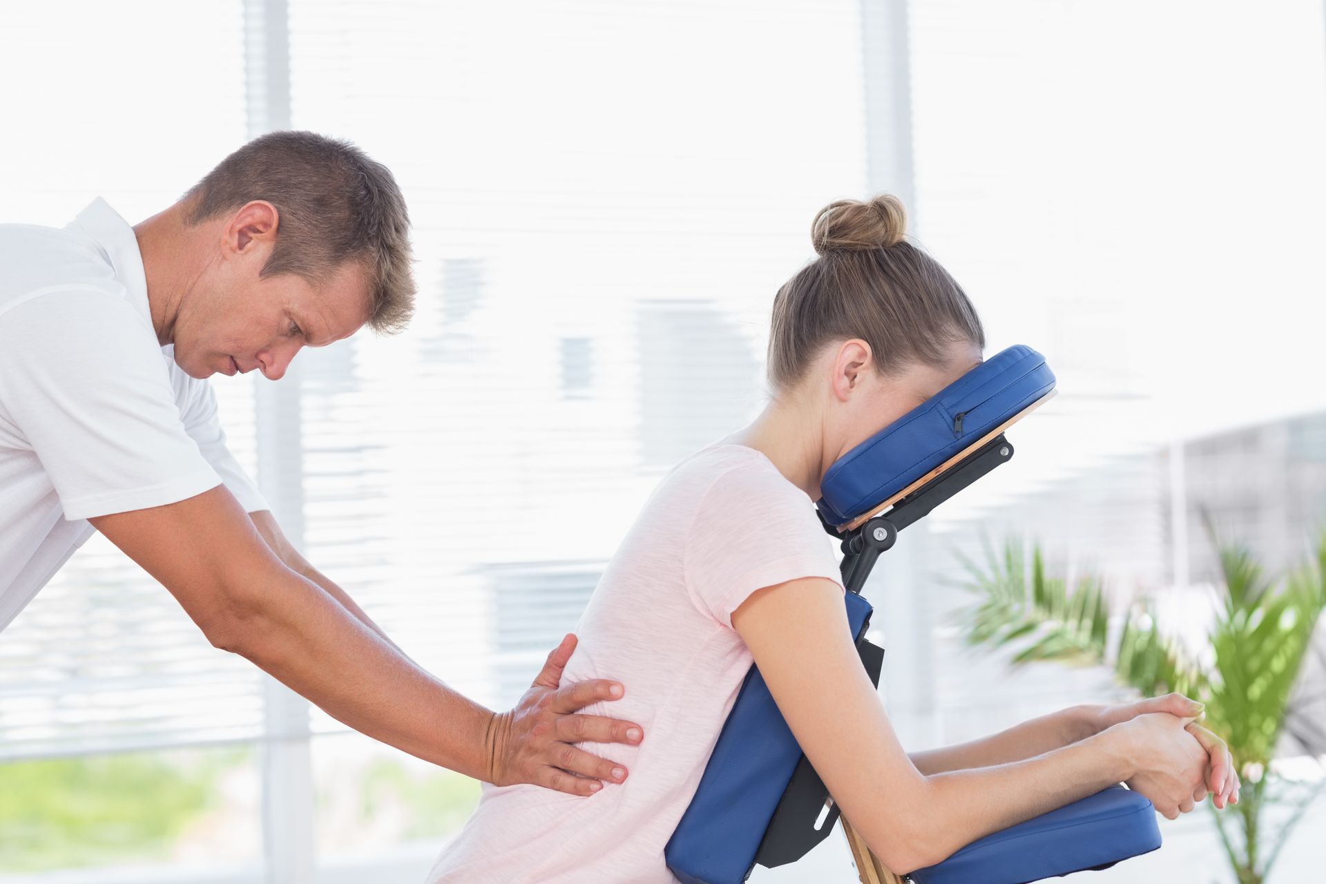 A man is giving a woman a massage in a chair.