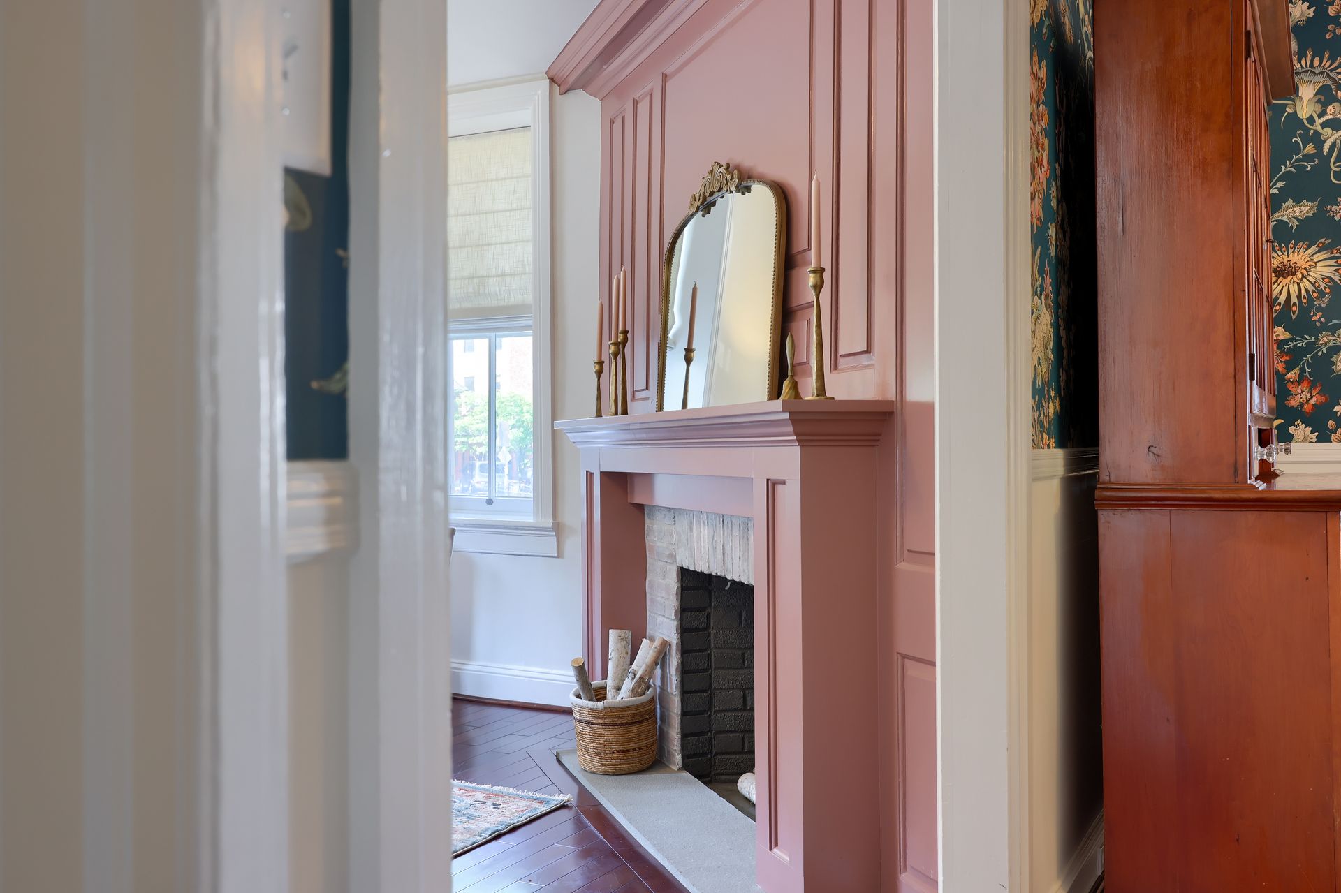 A living room with a pink fireplace and a mirror.