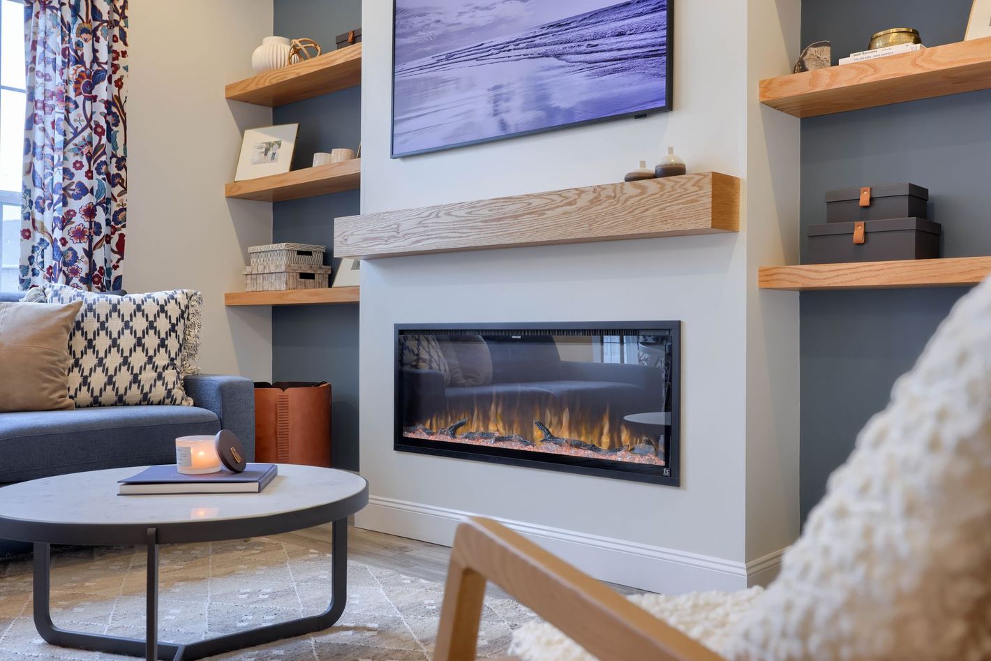 A living room with a custom fireplace , couch , chair , coffee table and television.