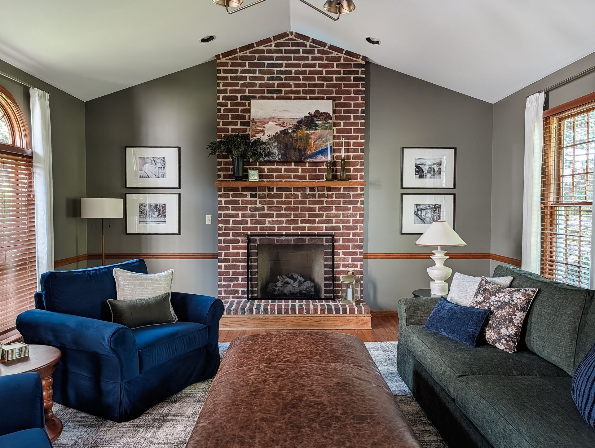 Tailored, traditional living room with muted green walls, leather ottoman, and oversized blue chairs
