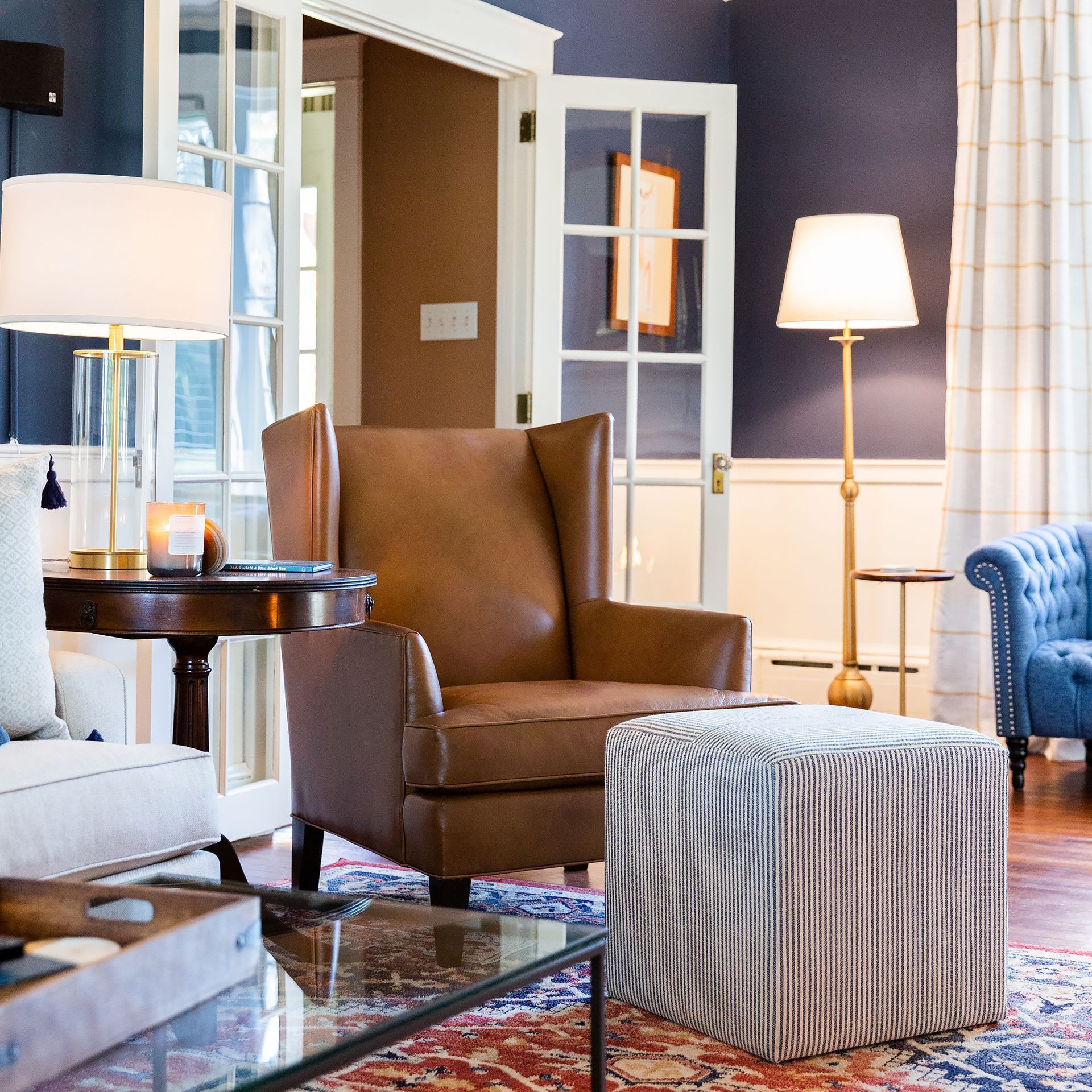 Navy blue living room with french doors and a modern leather wingback chair
