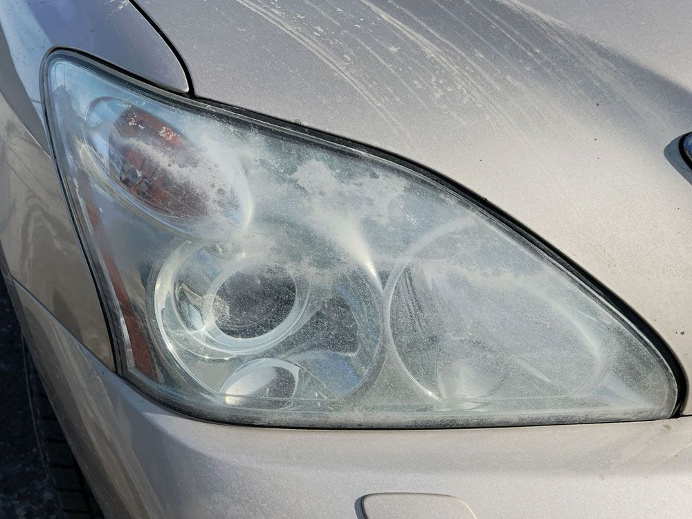 Close-up of a car headlight with cloudy, fogged lens on a silver vehicle