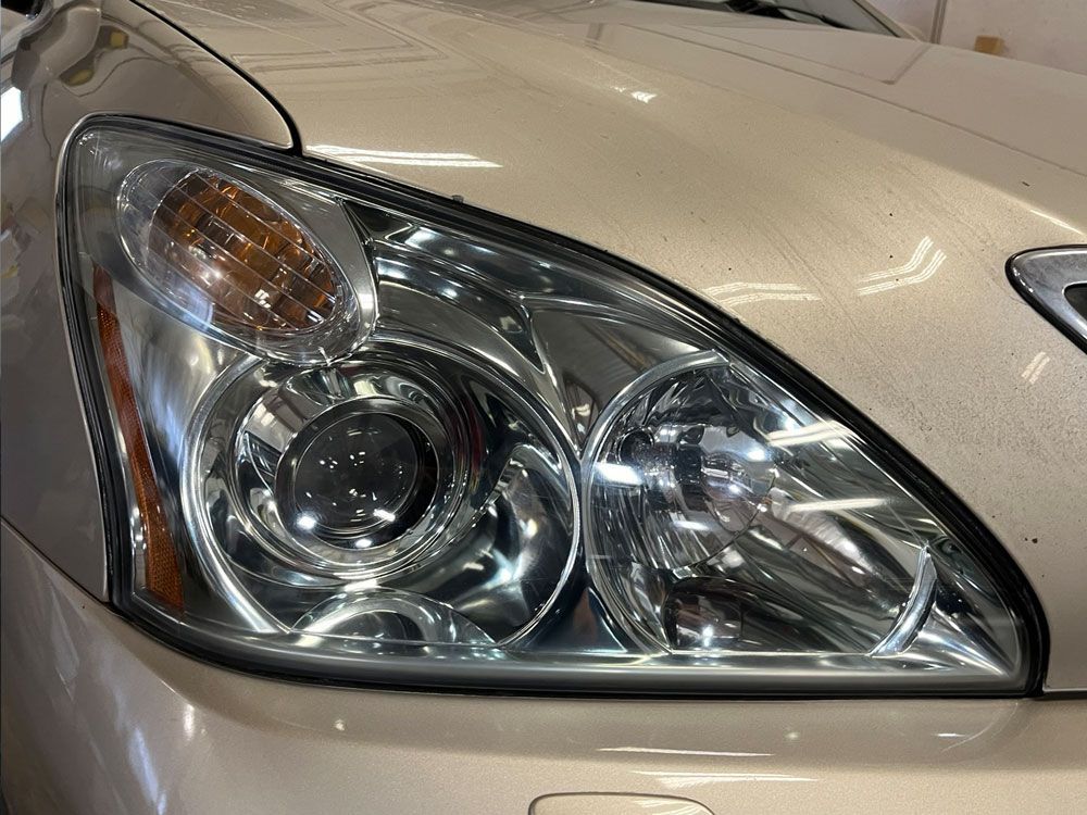 Close-up of a beige car headlight and front fender with chrome detailing