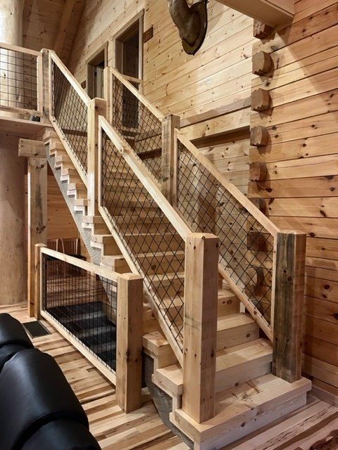 Wooden staircase with metal mesh railing in a log cabin.