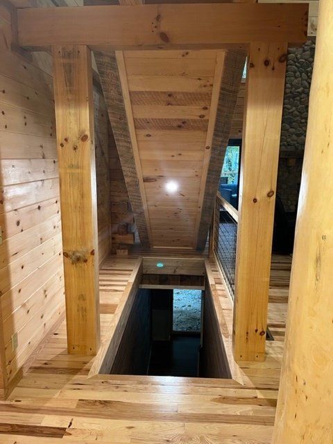 Wooden structure with opening to a dark space below; natural wood tones dominate.