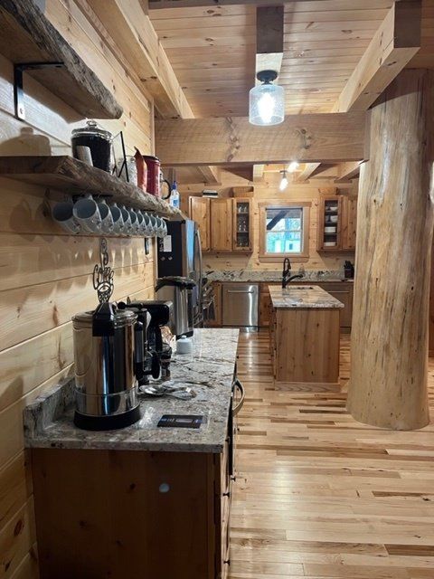 Wooden cabin kitchen with cabinets, island, appliances, and exposed beams.
