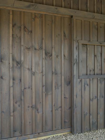 Gray wooden exterior wall with a small door, vertical planks.