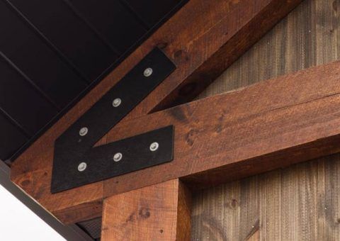 Wooden beams joined with black metal brackets and silver bolts.