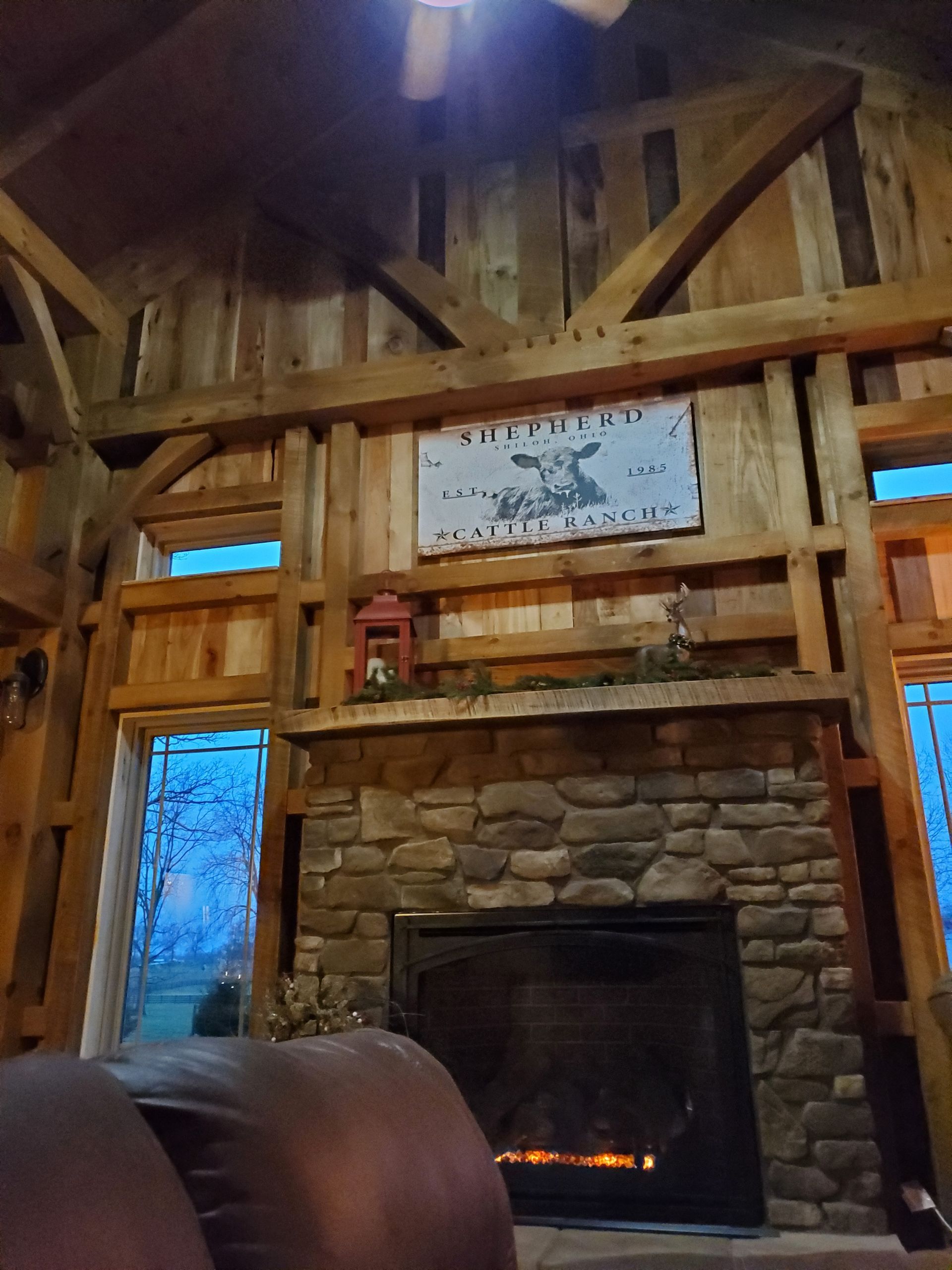 Cozy interior with stone fireplace, wooden beams, sign, and windows.