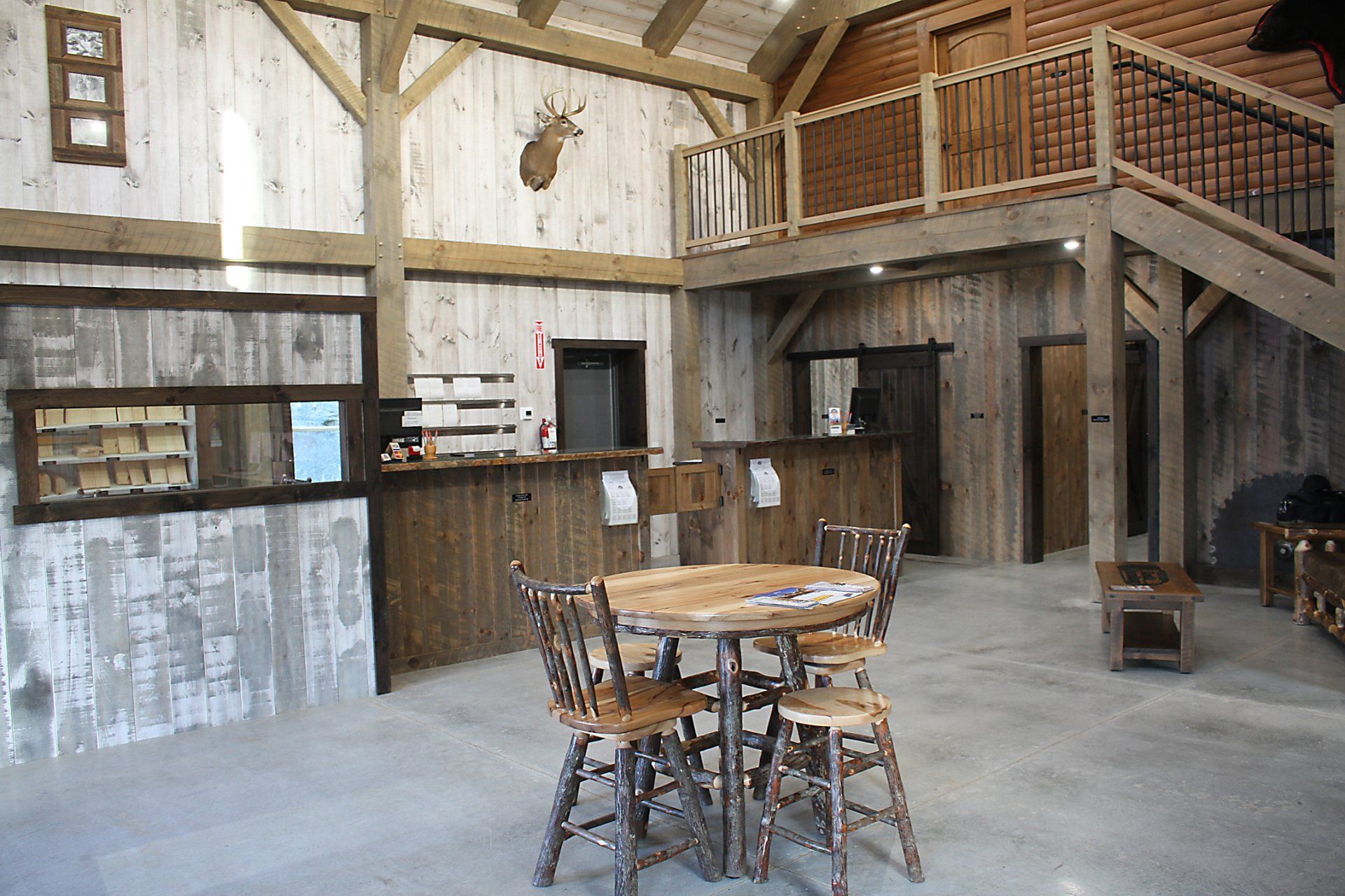 Rustic interior with wooden beams, a mezzanine, and a round table with chairs.