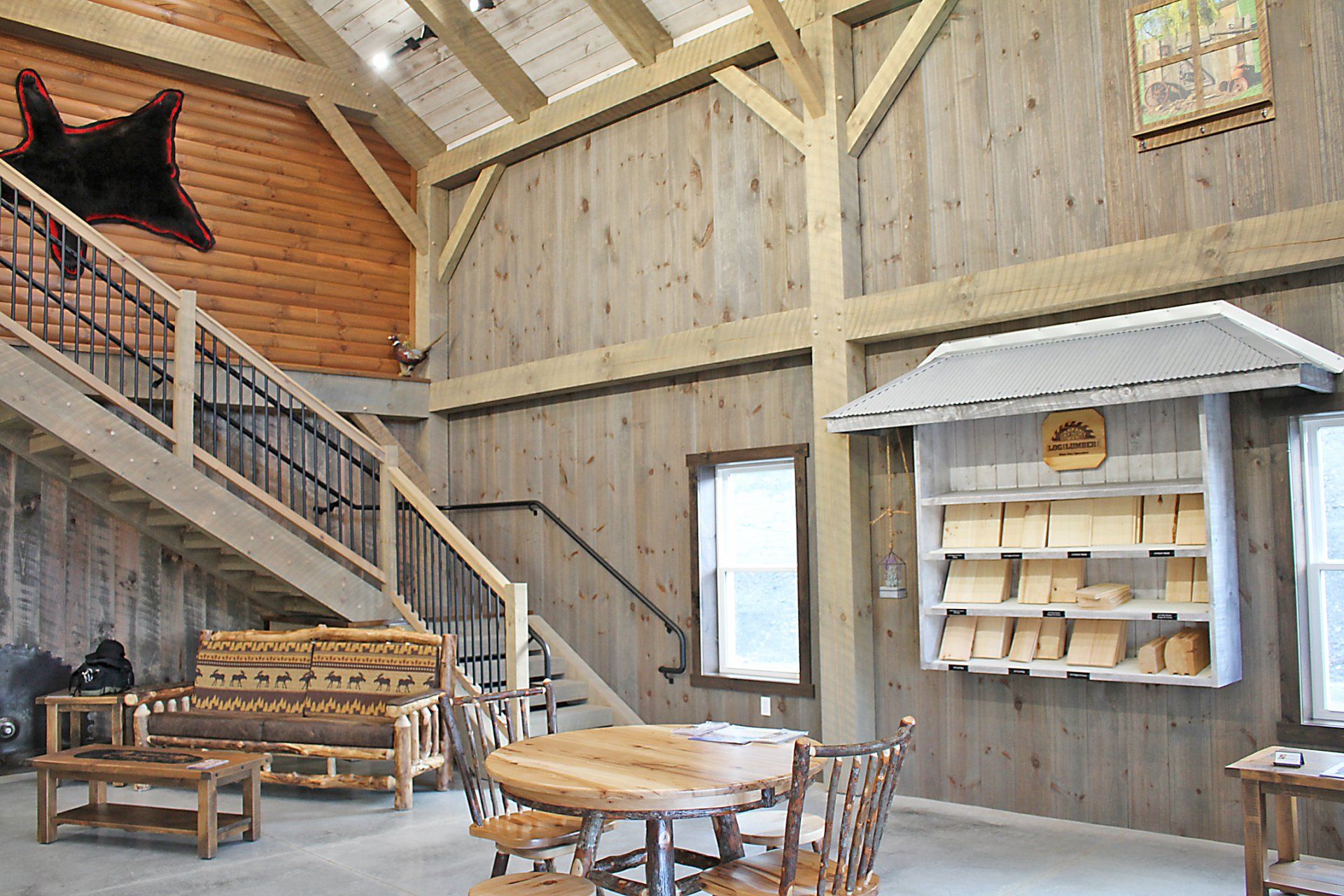 Interior of a rustic barn with wooden walls, staircase, seating area, and display case.