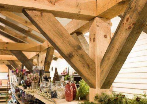Wooden timber frame structure, supporting a roof, with visible support beams.