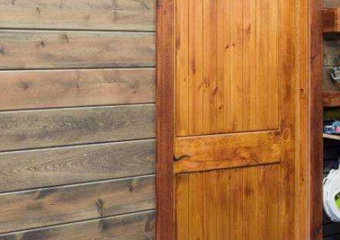 Wood-paneled wall and door. The wall is stained brown; the door is stained a lighter wood tone.