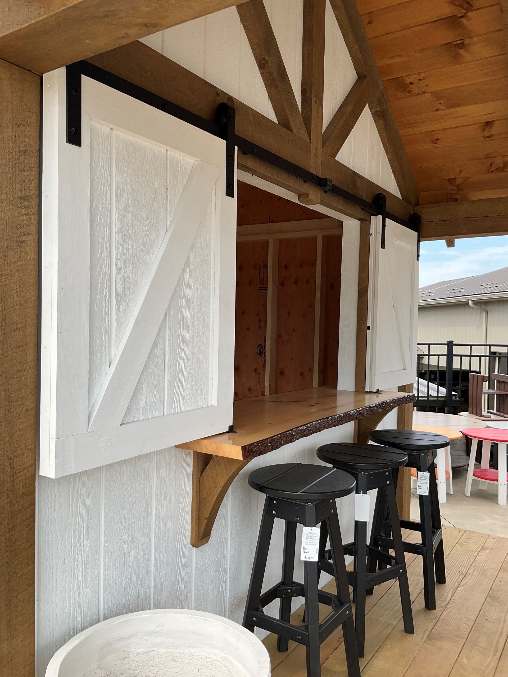 White barn doors slide open, revealing an outdoor bar with stools.