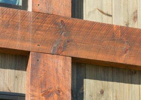 Cross of stained wooden beams on a wooden wall.