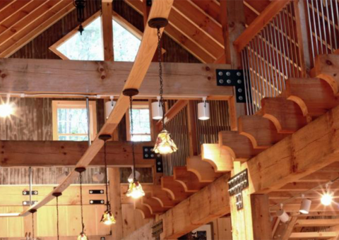Wooden interior with exposed beams, stairs, and hanging lights.