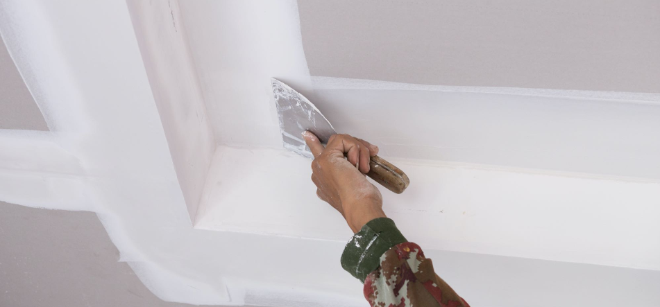 Primer plano de una pared turquesa con dos pequeños agujeros oscuros sobre una repisa blanca y amarilla.