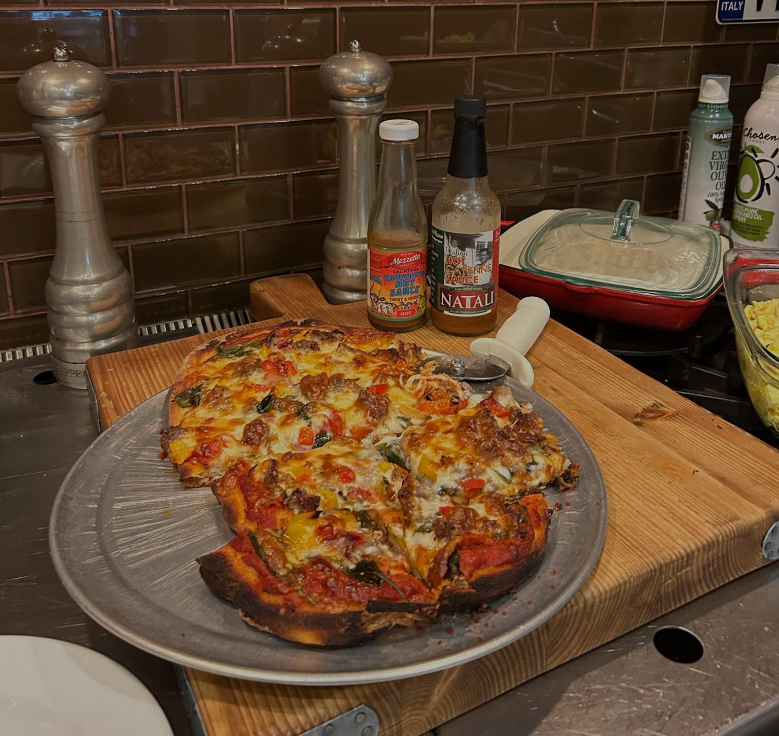 A pizza sitting on a cutting board next to a bottle of salsa