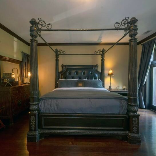 A bedroom with a four poster bed and a mirror
