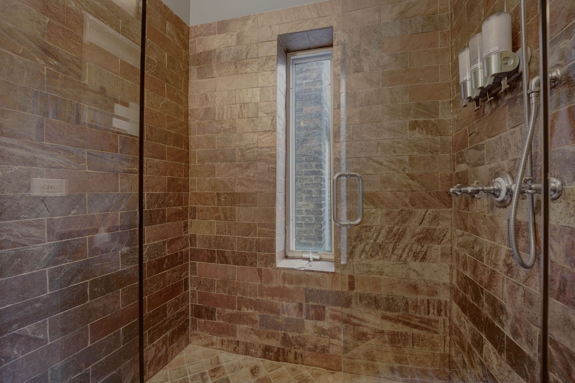 A bathroom with a walk in shower and a window.