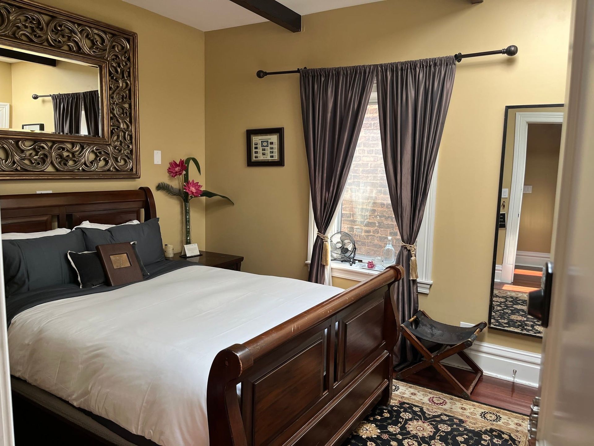 A bedroom with a sleigh bed and a large mirror
