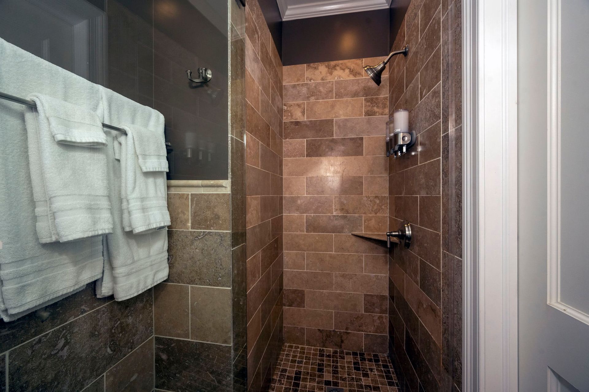 A bathroom with a walk in shower and towels hanging on the wall.