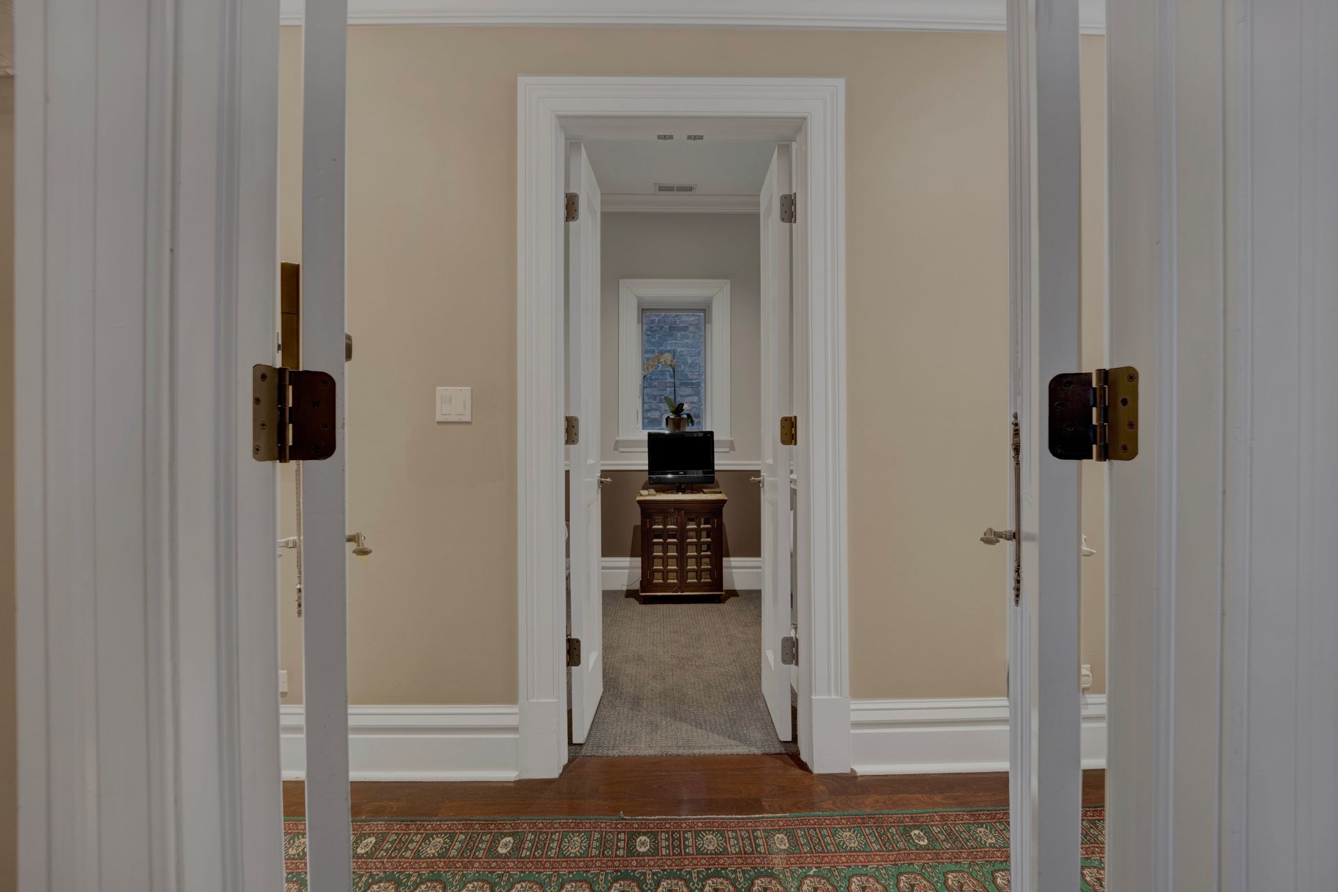 A hallway with two doors open leading to a room.
