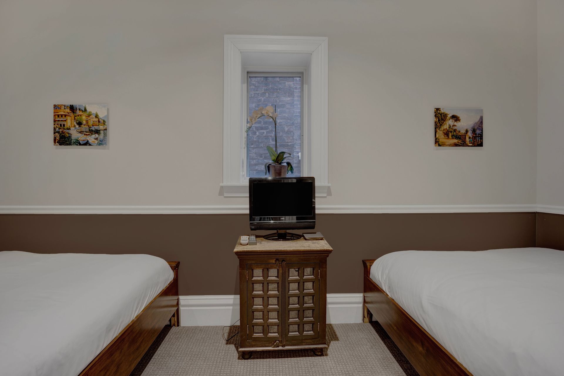 A hotel room with two beds , a television and a window.
