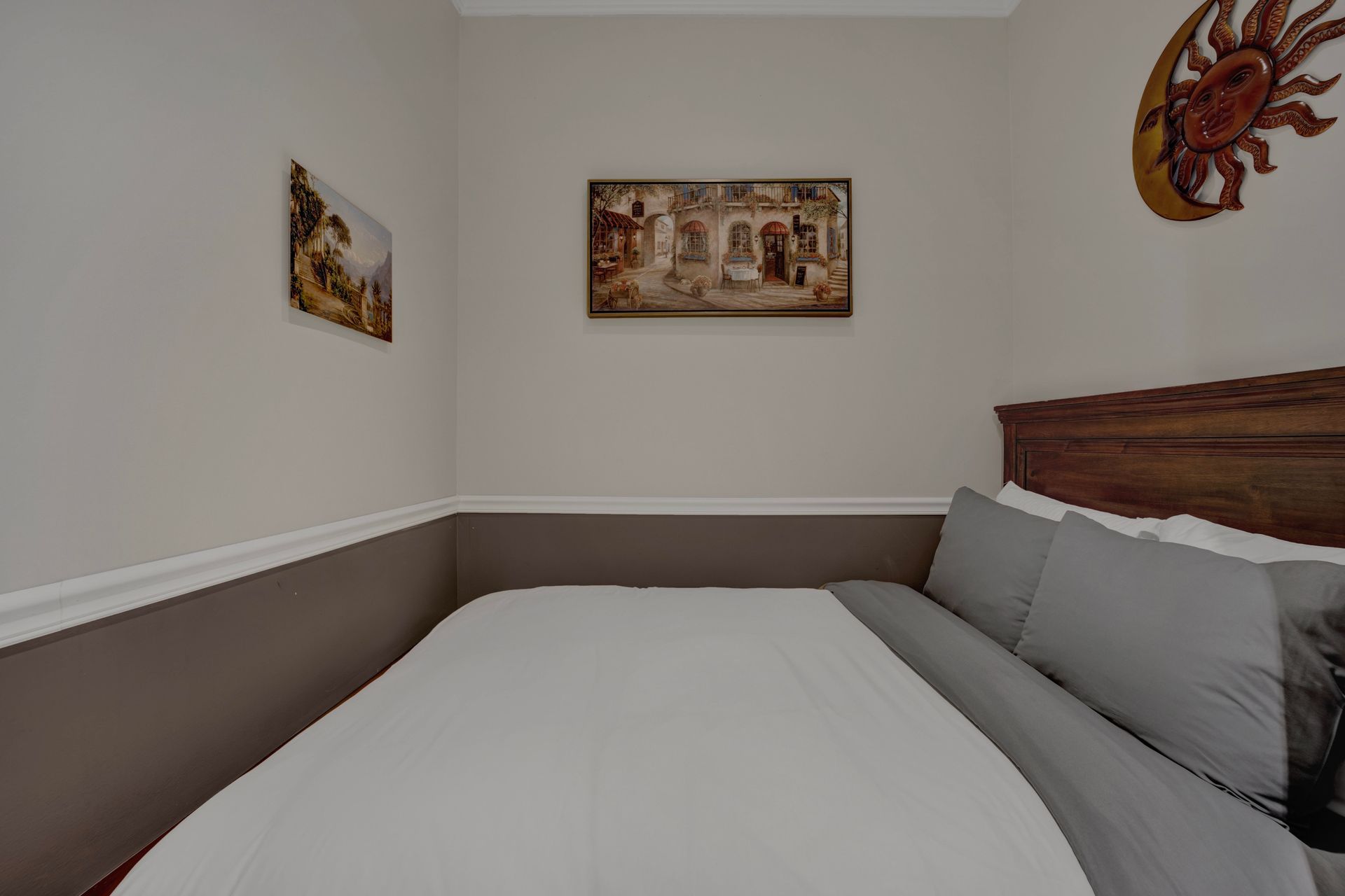 A bedroom with a bed , pillows and a painting on the wall.