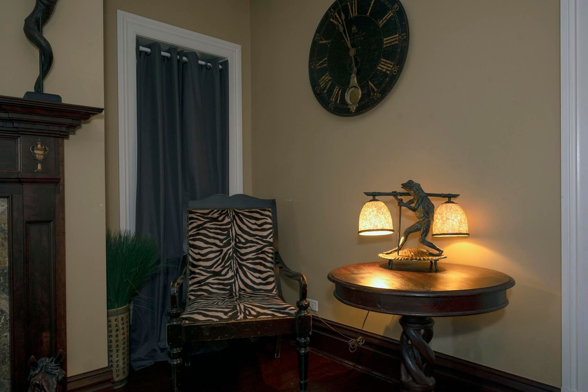A living room with a chair , table and clock on the wall.
