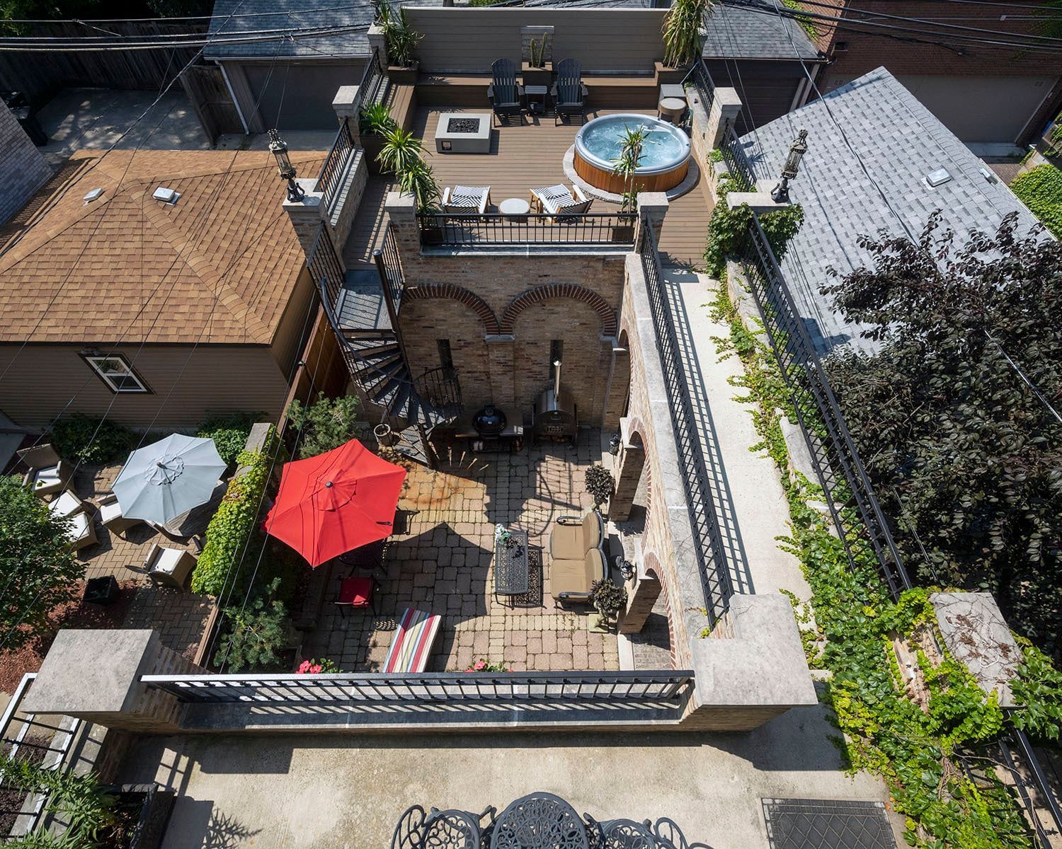 An aerial view of a patio with tables , chairs , umbrellas and a hot tub.