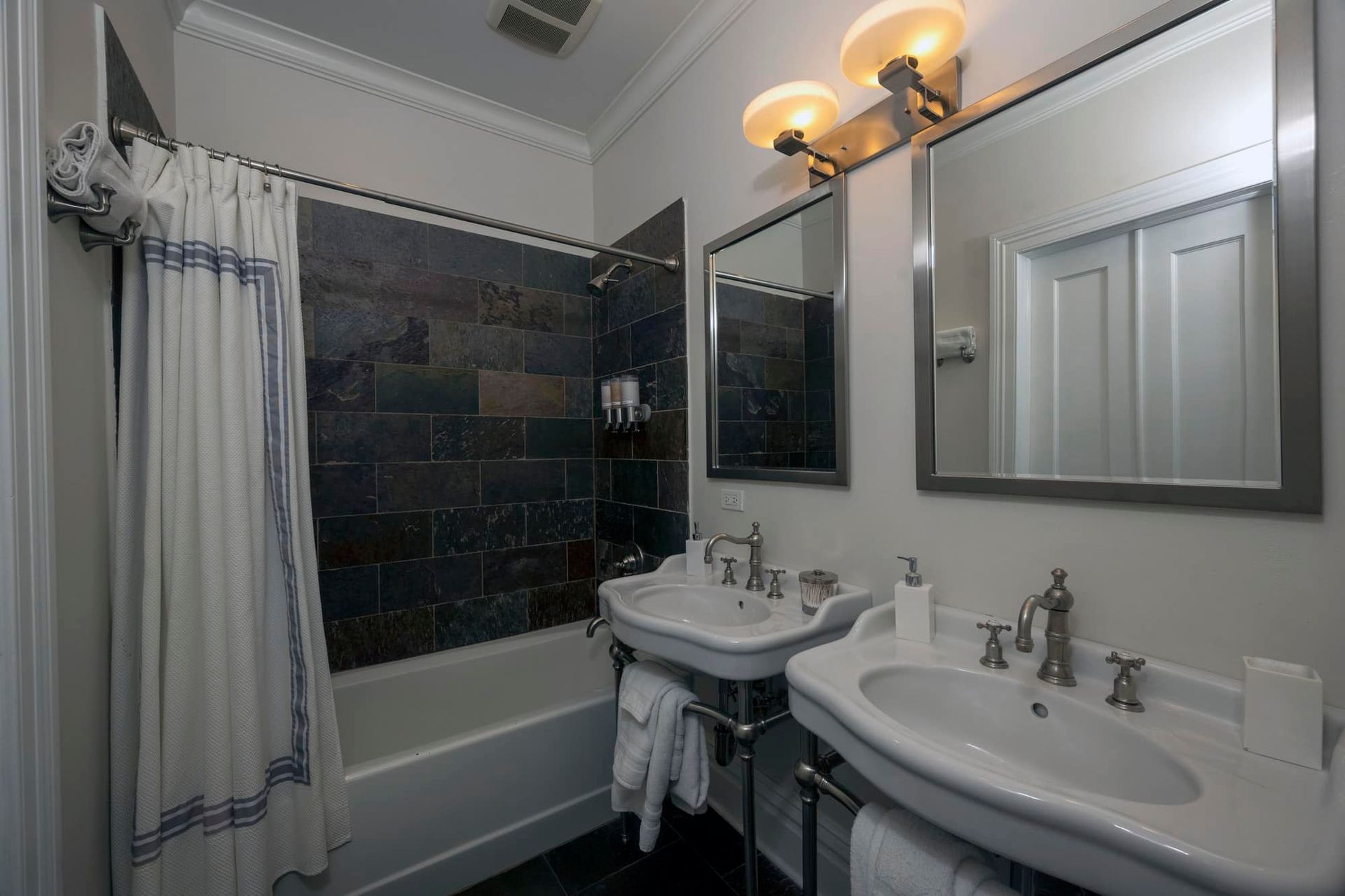 A bathroom with two sinks , a tub and two mirrors.