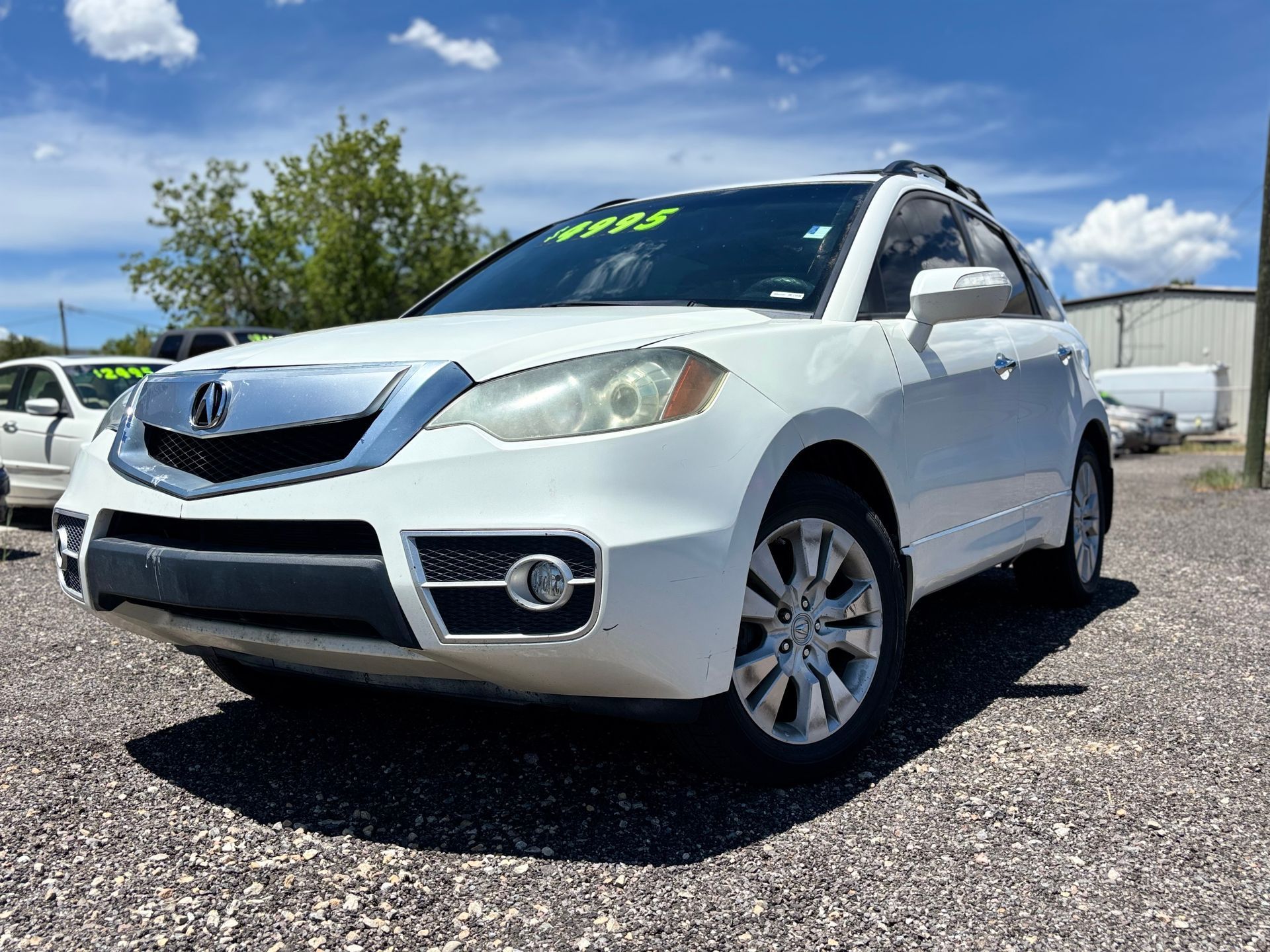Silver Acura SUV parked on a gravel lot under a blue sky