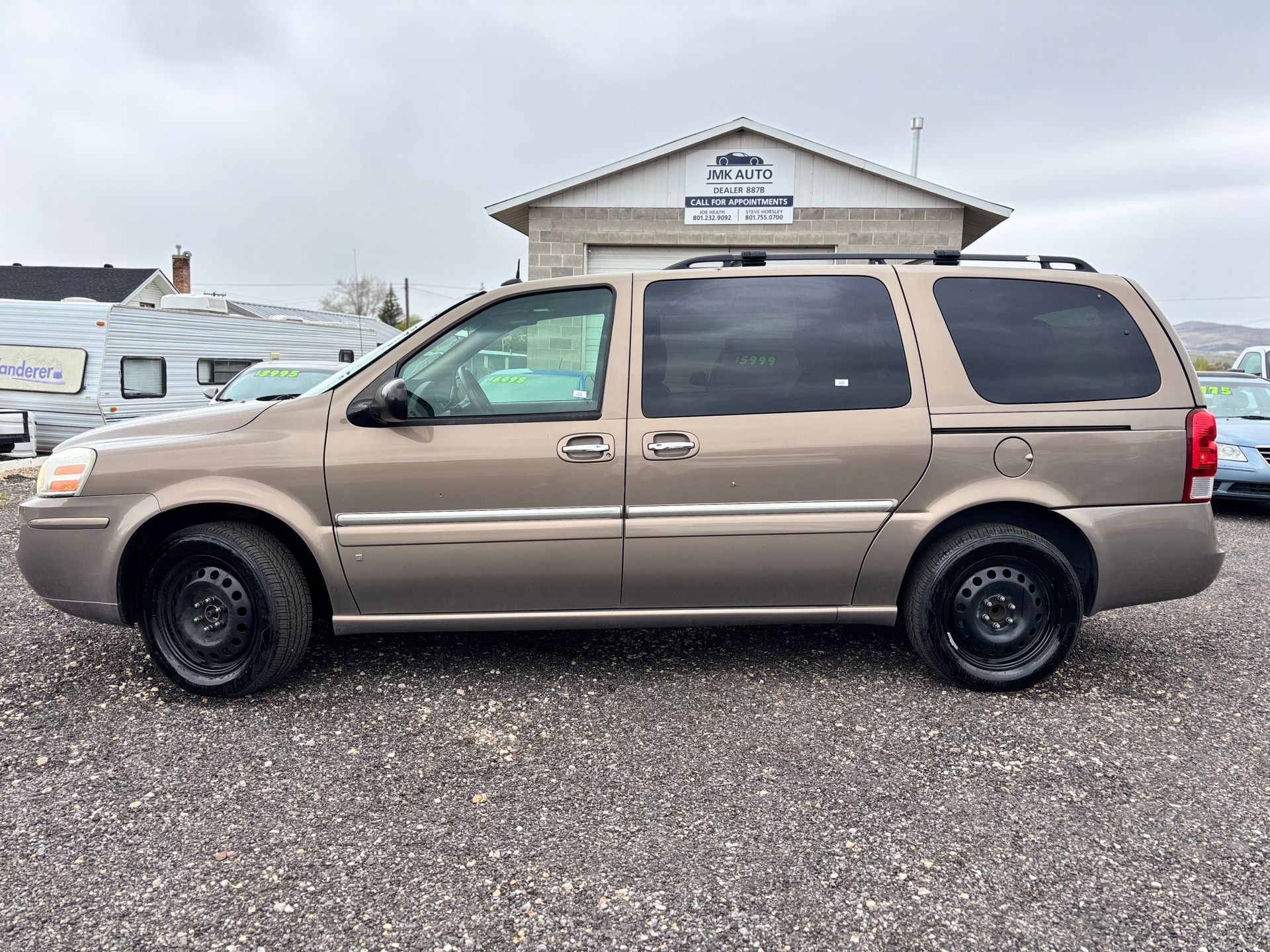 Tan SUV parked on gravel in front of a small building under an overcast sky