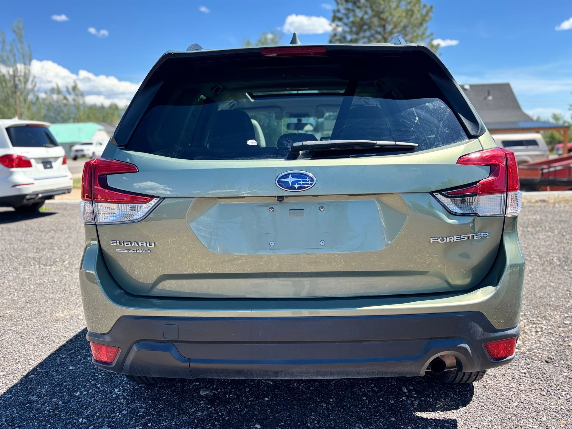 Rear view of a gray Subaru SUV parked in a lot on a sunny day