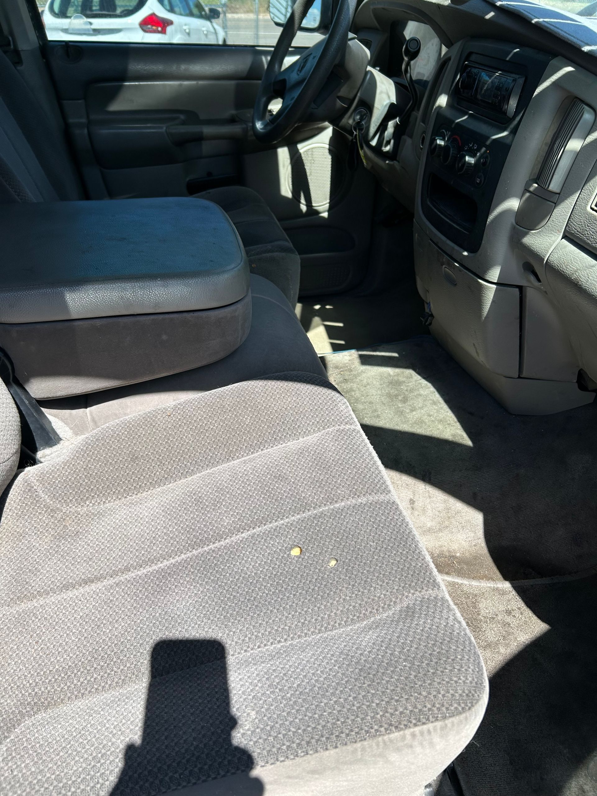 Car interior with gray cloth front seats, steering wheel, and center console in daylight