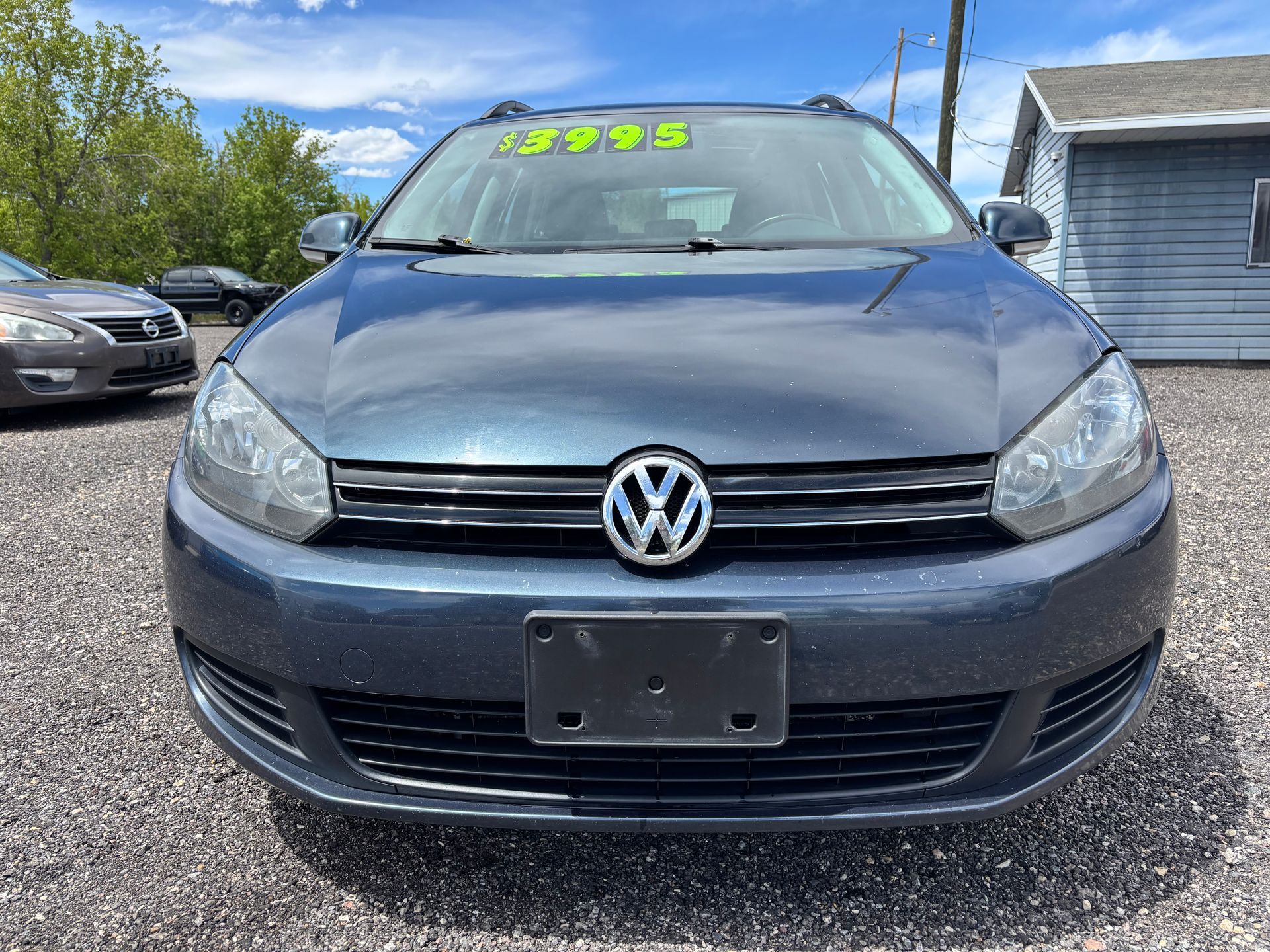 Front view of a blue Volkswagen car parked on a gravel lot