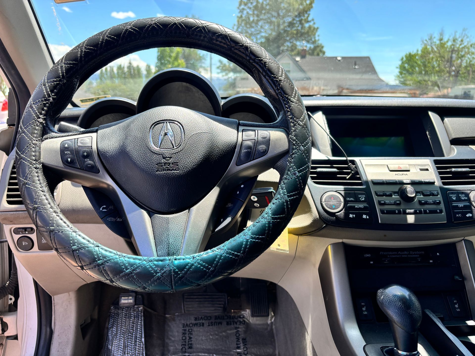 Car interior with steering wheel, dashboard, and center console, viewed from the driver’s seat.