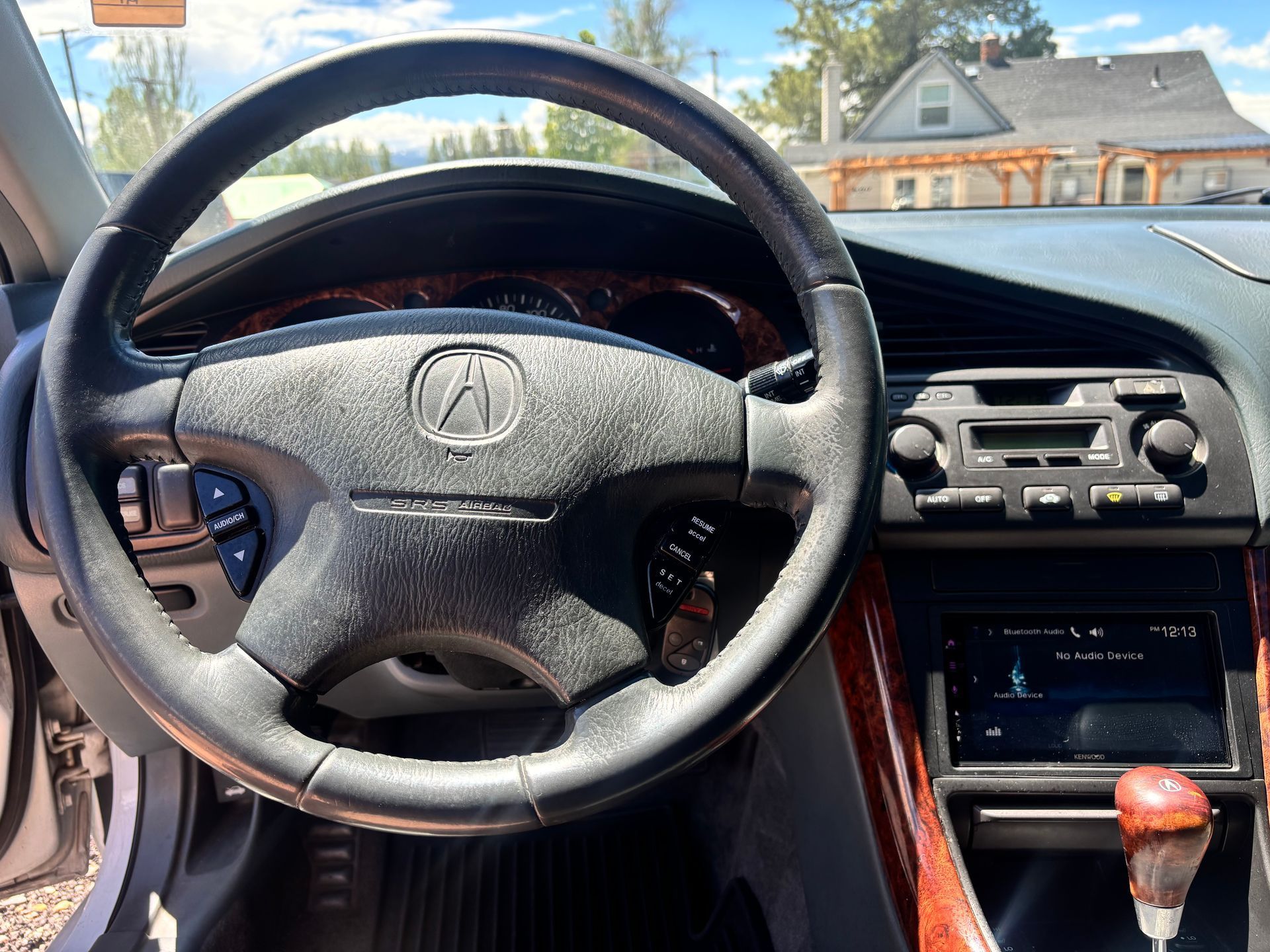 Car interior with Acura steering wheel, center console, and sunny street view through windshield