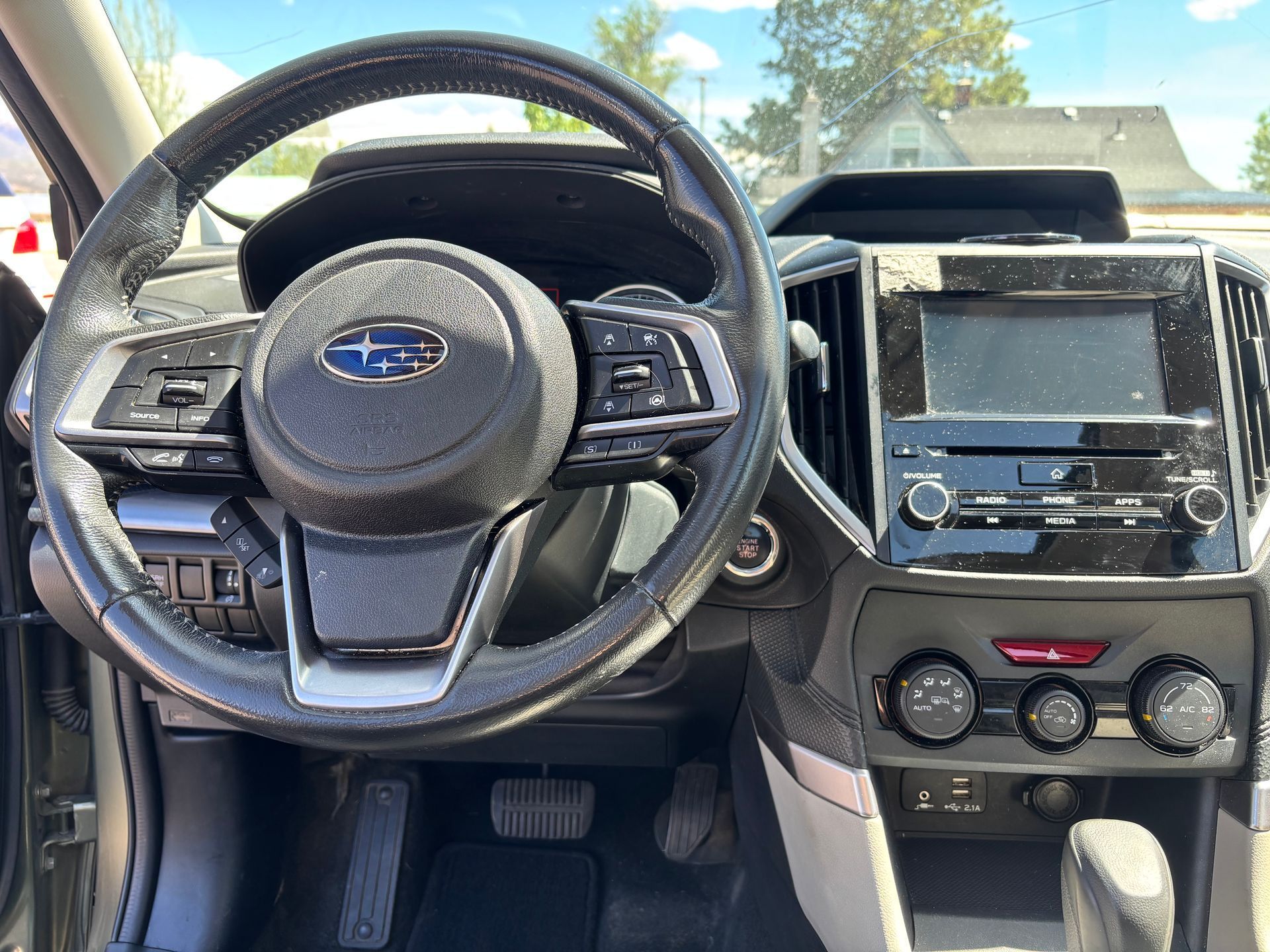 Car interior with Subaru steering wheel, dashboard, and center console in daylight