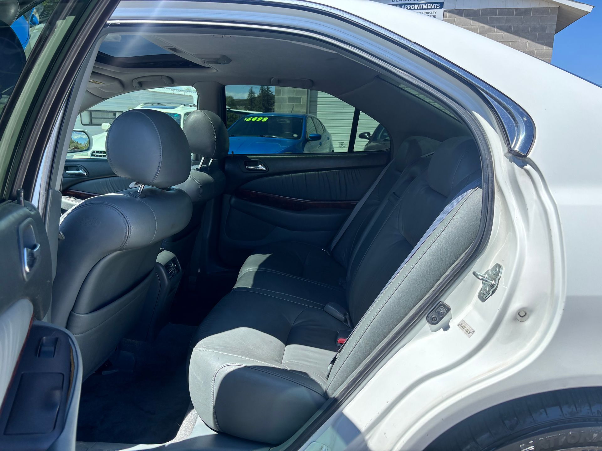 Open rear door of a silver sedan, showing black back seat and interior.