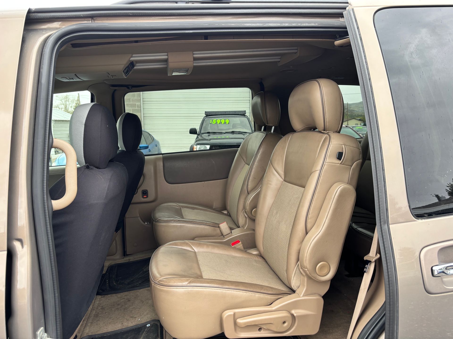Tan van with tan captain’s chairs and sliding door open, showing the interior seating area.