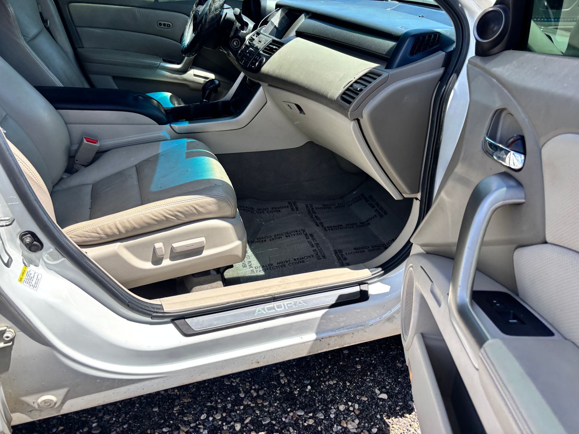 Open car door showing gray front passenger seat and beige dashboard interior