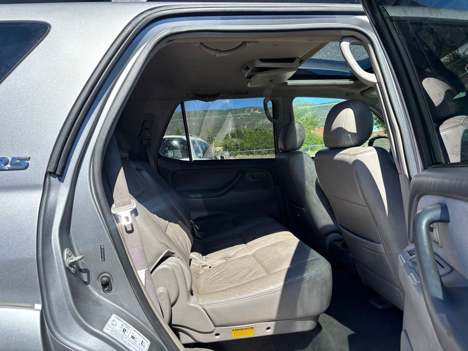 Open car door showing a beige back seat and interior upholstery.