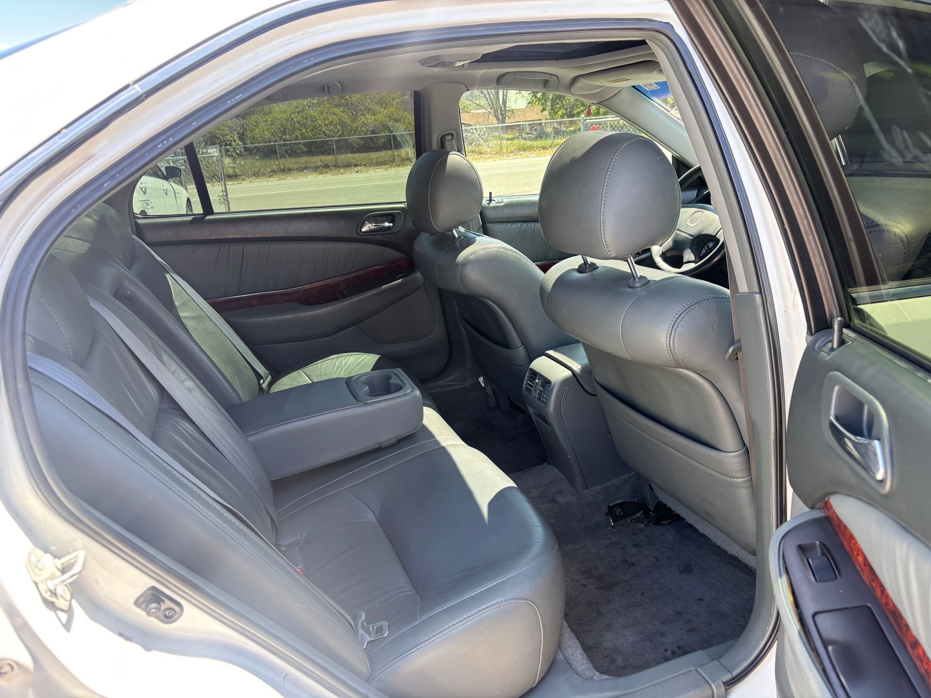 Open rear door of a gray sedan, showing gray leather back seat and front seat interior.