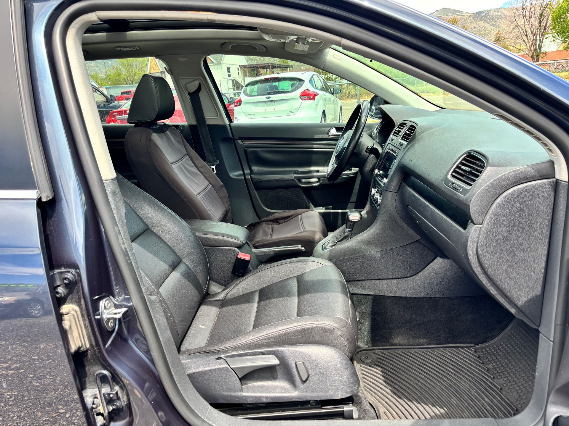 Open car door showing gray cloth front seats and dashboard interior