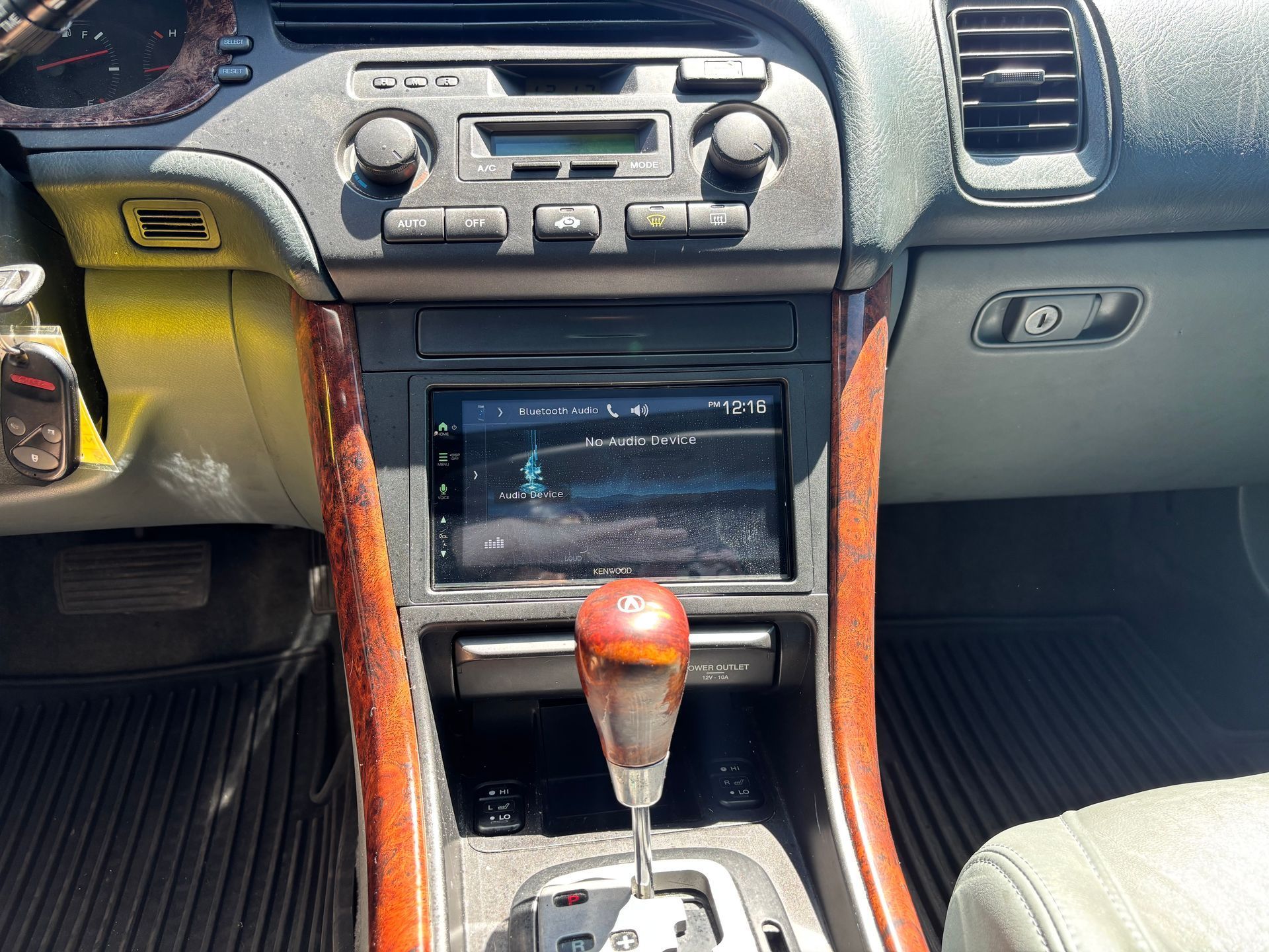 Car dashboard with a center console, touchscreen, and wood-trimmed automatic gear shift.
